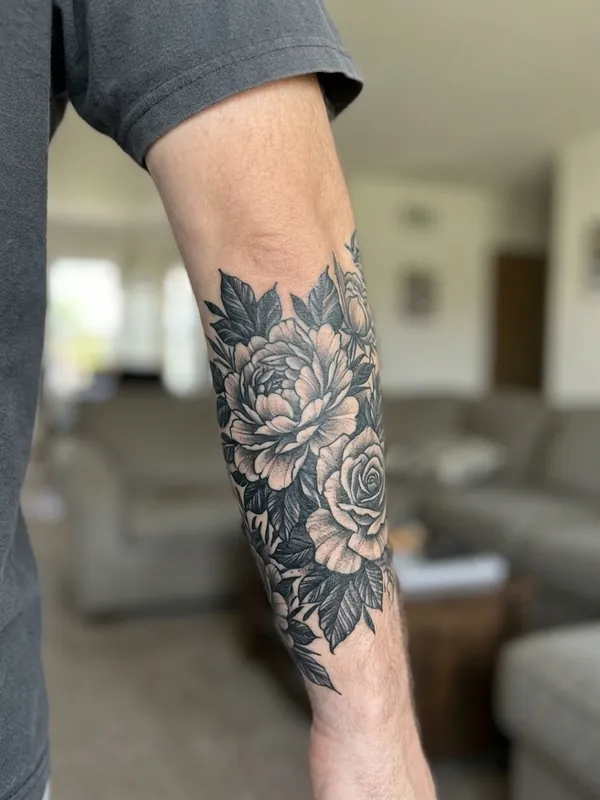 Dark floral cover-up tattoo on forearm hiding the old tribal tattoo